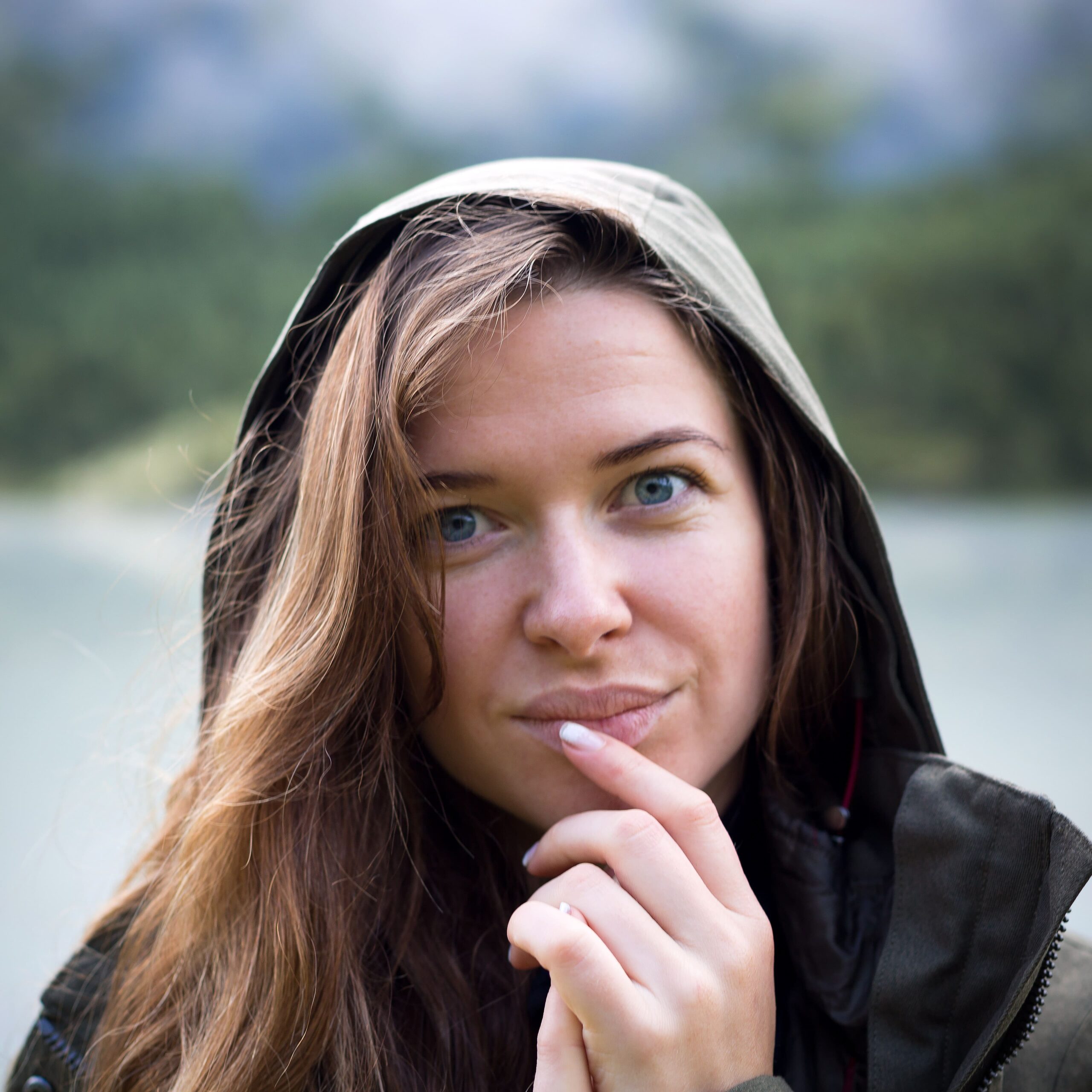 portrait-young-woman-hood-brings-her-fingers-her-lips-closeup (1)
